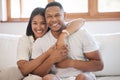 Portrait of a happy young African American couple hugging and sitting on a couch at home, smiling black husband and wife Royalty Free Stock Photo