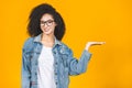 Portrait of a happy young african american curly woman pointing fingers away at copy space isolated over yellow background Royalty Free Stock Photo