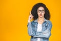 Portrait of a happy young african american curly woman pointing fingers up at copy space isolated over yellow background Royalty Free Stock Photo