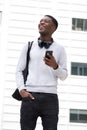 Happy young african american man with bag holding on cellphone outside Royalty Free Stock Photo