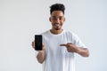 Portrait of happy young african american man holding mobile phone and pointing to screen Royalty Free Stock Photo
