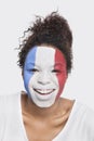 Portrait of happy young African American woman with French flag painted on face against white background Royalty Free Stock Photo