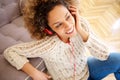 Happy young african american woman sitting on floor and listening to music with headphones Royalty Free Stock Photo