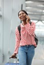 Happy young african american woman walking and talking with cellphone in airport terminal Royalty Free Stock Photo