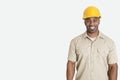 Portrait of happy young African man wearing yellow hard hat helmet over gray background Royalty Free Stock Photo