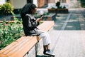 Portrait of happy young african woman sitting outside on bench reading a text message on her mobile phone