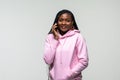 Portrait of happy young african woman talking on mobile phone and looking up while standing against white background Royalty Free Stock Photo