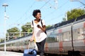 African woman traveler standing with cellphone and on railway platform