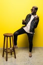 Portrait of a happy young afro american man listening to music with headphones and playing on invisible guitar over yello Royalty Free Stock Photo