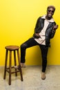 Portrait of a happy young afro american man listening to music with headphones and playing on invisible guitar over yello Royalty Free Stock Photo