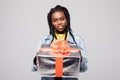 Portrait of a happy young afro american woman holding present box isolated over gray background Royalty Free Stock Photo