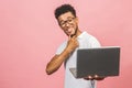 Portrait of happy young afroamerican man using laptop comruter and checkin isolated against pink