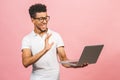 Portrait of happy young afroamerican man using laptop comruter and checkin isolated against pink