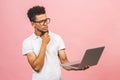 Portrait of happy young afroamerican man using laptop comruter and checkin isolated against pink