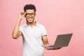 Portrait of happy young afroamerican man using laptop comruter and checkin isolated against pink