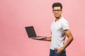 Portrait of happy young afroamerican man using laptop comruter and checkin isolated against pink