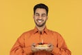 Portrait Of Happy Young Arab Man Holding Piece Of Cake With Candle