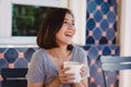 Portrait of happy young asian business woman with mug in hands drinking coffee in the morning at cafe. Royalty Free Stock Photo