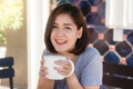 Portrait of happy young asian business woman with mug in hands drinking coffee in the morning at cafe. Royalty Free Stock Photo