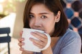 Portrait of happy young asian business woman with mug in hands drinking coffee in the morning at cafe. Royalty Free Stock Photo