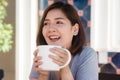 Portrait of happy young asian business woman with mug in hands drinking coffee in the morning at cafe. Royalty Free Stock Photo