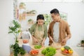 Portrait of happy young Asian couple cooking together in the kitchen at home Royalty Free Stock Photo