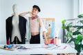 Portrait of happy young Asian LGBTQ gay dressmaker standing confident pose with mannequin behind working desk, sketch of fashion Royalty Free Stock Photo