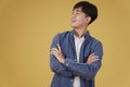 Portrait of happy young asian man dressed casually with folded crossed arms gesture isolated on yellow background Royalty Free Stock Photo