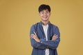 Portrait of happy young asian man dressed casually with folded crossed arms gesture isolated on yellow background Royalty Free Stock Photo