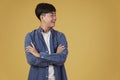 Portrait of happy young asian man dressed casually with folded crossed arms gesture isolated on yellow background Royalty Free Stock Photo