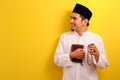 Portrait of happy Young Asian Muslim man holding Quran and prayer beads looking at a copy space aside Royalty Free Stock Photo