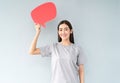 Portrait of a happy young asian woman while holding up speech bubble icons  over grey background Royalty Free Stock Photo