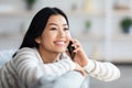 Portrait Of Happy Young Asian Woman Talking On Mobile Phone At Home