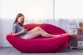 Portrait happy young asian woman using smart phone at house or living room on red sofa with happy, smiley face. Attractive girl Royalty Free Stock Photo