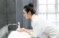 Portrait of happy young Asian woman while washing her face and  looking to mirror at bathroom.Natural skin care and people Concept Royalty Free Stock Photo