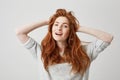 Portrait of happy young beautiful redhead girl smiling looking at camera touching hair over white background. Royalty Free Stock Photo