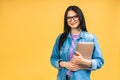 Portrait of happy young beautiful surprised woman with glasses standing with laptop isolated on yellow background. Royalty Free Stock Photo