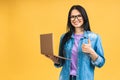 Portrait of happy young beautiful surprised woman with glasses standing with laptop isolated on yellow background. Space for text Royalty Free Stock Photo