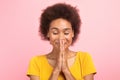 Portrait of happy young black curly lady with closed eyes meditating, praying with hands Royalty Free Stock Photo