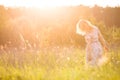 Portrait of happy young blond woman running on a meadow on a sunny summer day. Girl dancing on the grass in the park Royalty Free Stock Photo