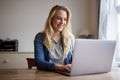 Happy young blond woman using laptop at home Royalty Free Stock Photo