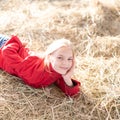 portrait happy of young blonde girl lying on haystack illuminated by bright sunshine. teenager on summer school vacation