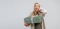 Portrait of Happy young blonde woman in trendy shirt holding big green gift box and looking at the camera over gray background. Royalty Free Stock Photo