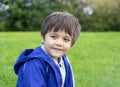 Portrait of Happy young boy sitting in the park, Active child looking out with smiling face sitting on green grass field, Kid Royalty Free Stock Photo