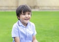 Portrait of Happy young boy sitting in the park, Active child looking out with smiling face sitting on green grass field, Kid Royalty Free Stock Photo