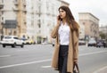 Portrait of happy young brunette woman in beige coat talking on Royalty Free Stock Photo