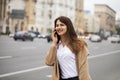 Portrait of happy young brunette woman in beige coat talking on Royalty Free Stock Photo