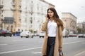 Portrait of happy young brunette woman in beige coat talking on Royalty Free Stock Photo