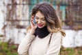 Portrait of happy young brunette woman in beige coat talking on Royalty Free Stock Photo