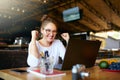 Portrait of happy young business woman celebrating success with arms up in front of laptop. Mixed race female won a lot Royalty Free Stock Photo